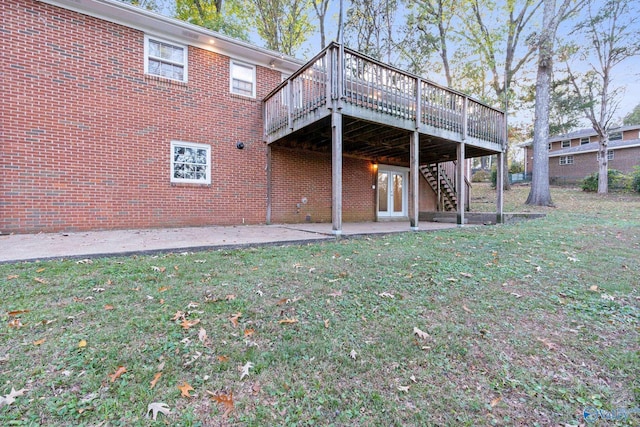 rear view of property featuring a lawn, a deck, and a patio