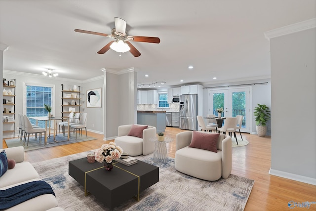 living room featuring ceiling fan, ornamental molding, and light wood-type flooring