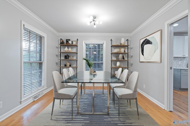 dining room featuring a textured ceiling, light wood-type flooring, and crown molding