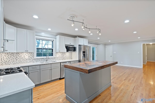 kitchen featuring a center island, crown molding, sink, appliances with stainless steel finishes, and light hardwood / wood-style floors