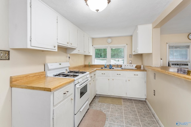 kitchen with white cabinets, a textured ceiling, white range with gas stovetop, and light tile patterned floors