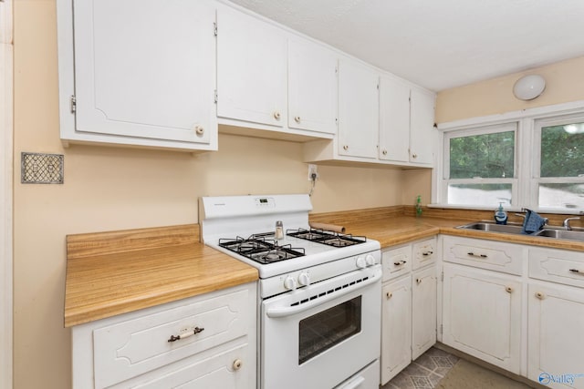 kitchen with white gas range oven, sink, and white cabinets