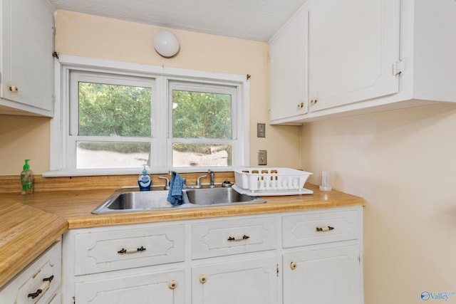 kitchen with white cabinets, sink, and a textured ceiling