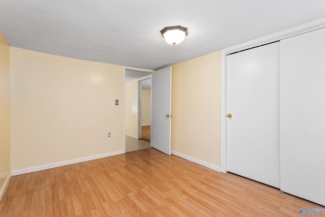 unfurnished bedroom with light wood-type flooring and a closet