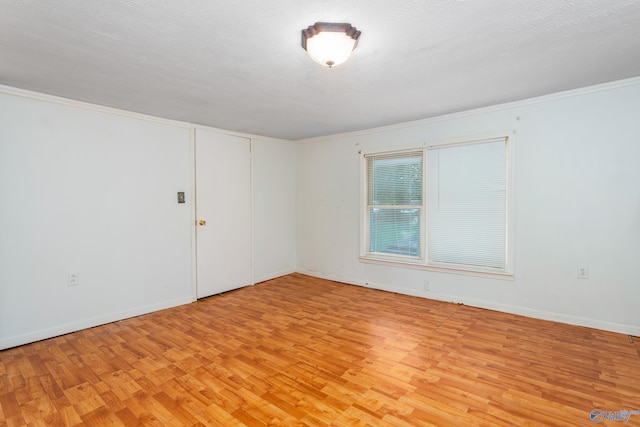 empty room featuring a textured ceiling, crown molding, and light hardwood / wood-style flooring