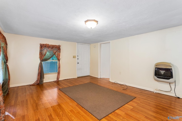 exercise room featuring a textured ceiling, wood-type flooring, and heating unit