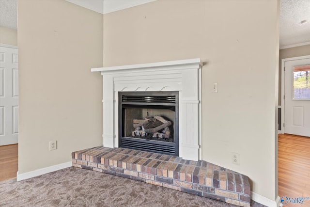 interior details with crown molding, carpet flooring, a fireplace with raised hearth, baseboards, and a textured ceiling
