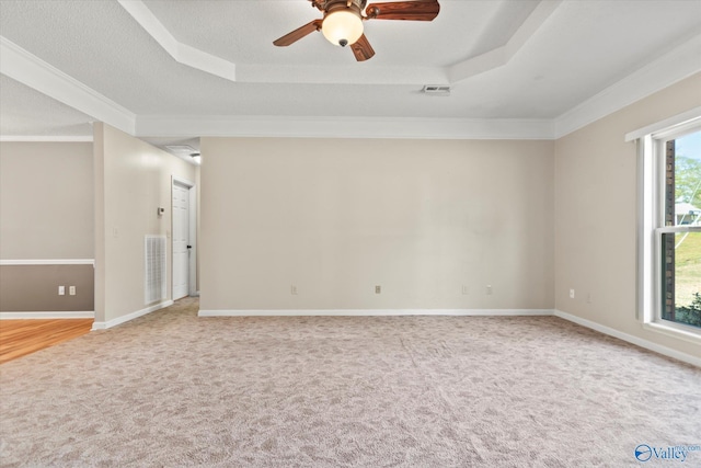 empty room with light carpet, a tray ceiling, and visible vents