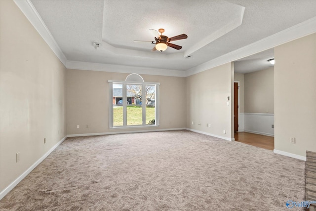 carpeted empty room with a tray ceiling, baseboards, a textured ceiling, visible vents, and a ceiling fan