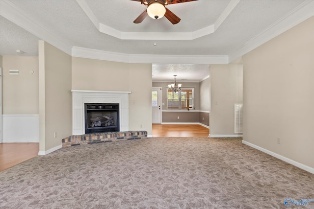 unfurnished living room featuring a textured ceiling, carpet floors, a tray ceiling, and ceiling fan with notable chandelier