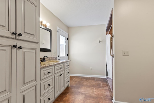 bathroom featuring baseboards, vanity, and a textured ceiling