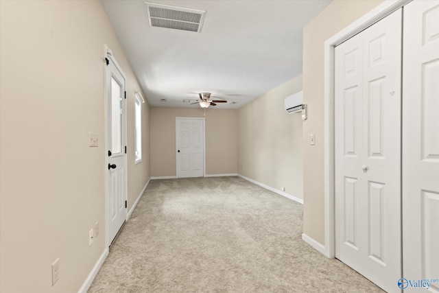 unfurnished room featuring a wall mounted AC, baseboards, visible vents, a ceiling fan, and light carpet