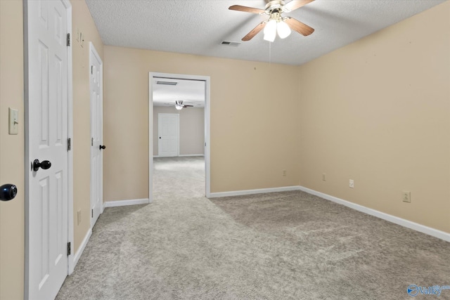 carpeted empty room with visible vents, a textured ceiling, baseboards, and ceiling fan