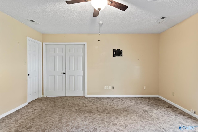 unfurnished bedroom featuring baseboards, carpet floors, a textured ceiling, and visible vents