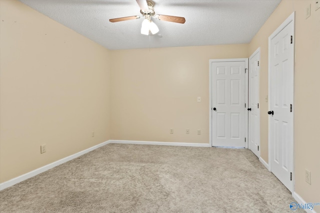 carpeted empty room with baseboards, ceiling fan, and a textured ceiling