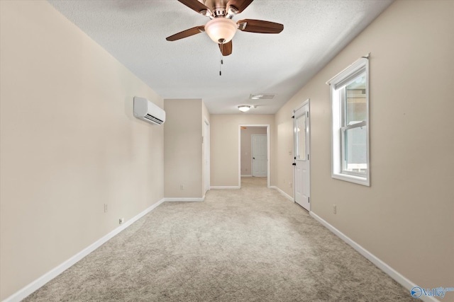 unfurnished room featuring baseboards, a textured ceiling, a wall unit AC, and light carpet