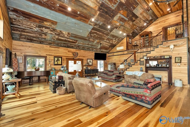 living room featuring beamed ceiling, wooden walls, wood-type flooring, and high vaulted ceiling