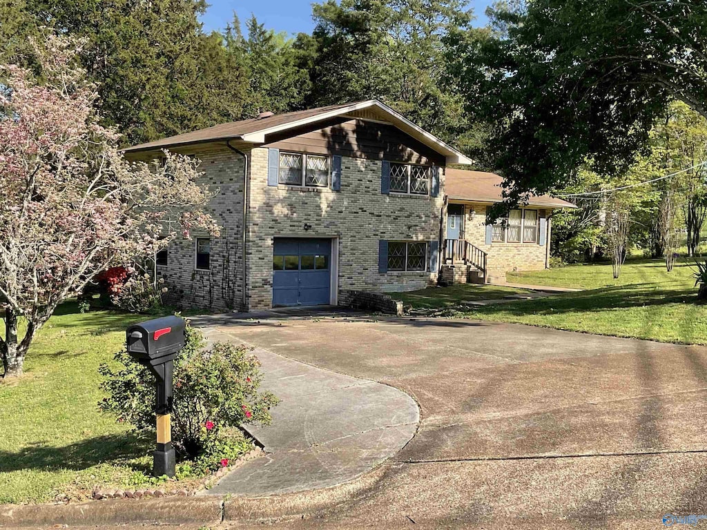 view of front of house featuring a garage, driveway, a front lawn, and brick siding