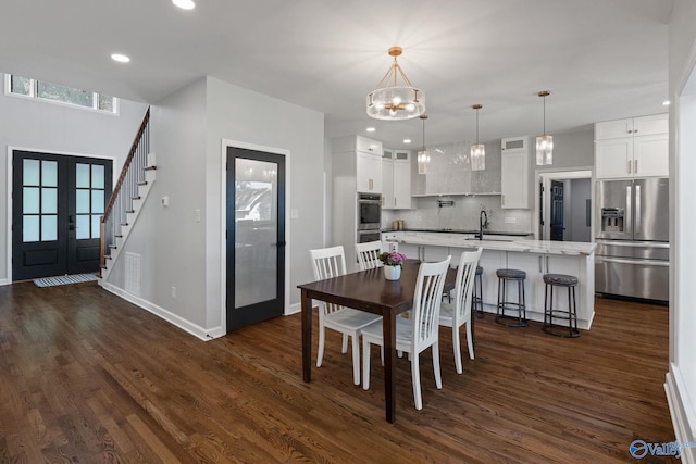 dining room with french doors, sink, dark wood-type flooring, and a notable chandelier