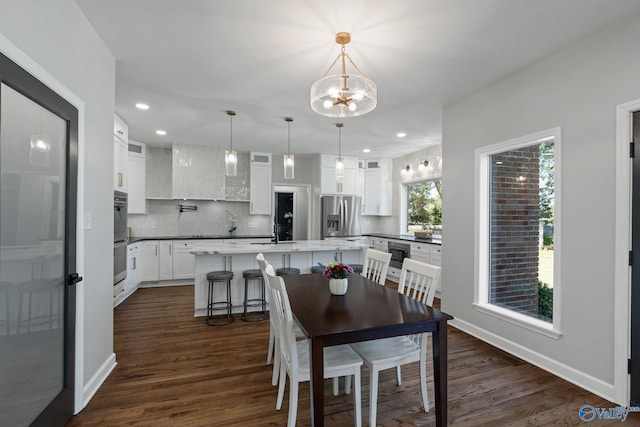 dining space with a notable chandelier, sink, and dark hardwood / wood-style floors