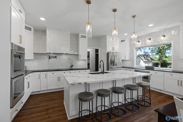 kitchen with a center island with sink, white cabinets, appliances with stainless steel finishes, and sink