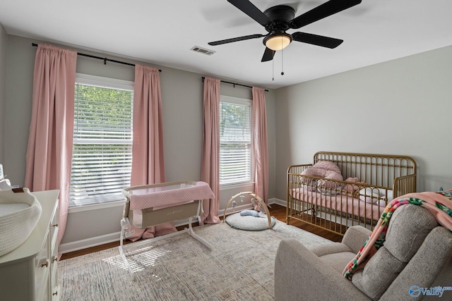 bedroom featuring a crib, hardwood / wood-style floors, and ceiling fan