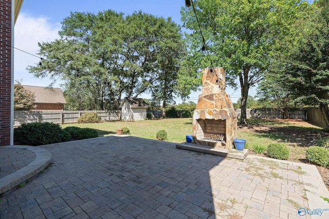 view of patio with an outdoor stone fireplace and a shed