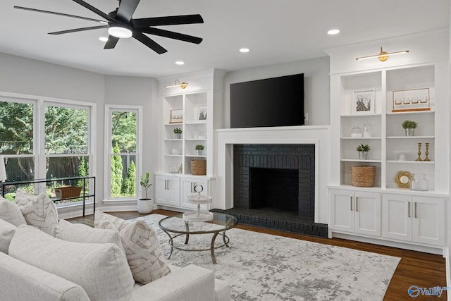 living room with ceiling fan, a brick fireplace, plenty of natural light, and dark hardwood / wood-style flooring