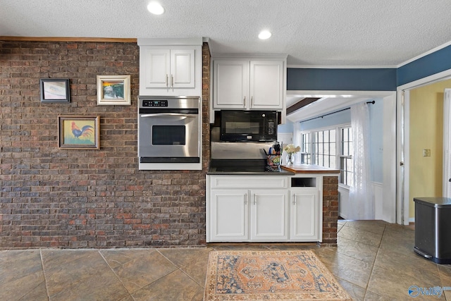 kitchen featuring brick wall, white cabinetry, a textured ceiling, and black appliances