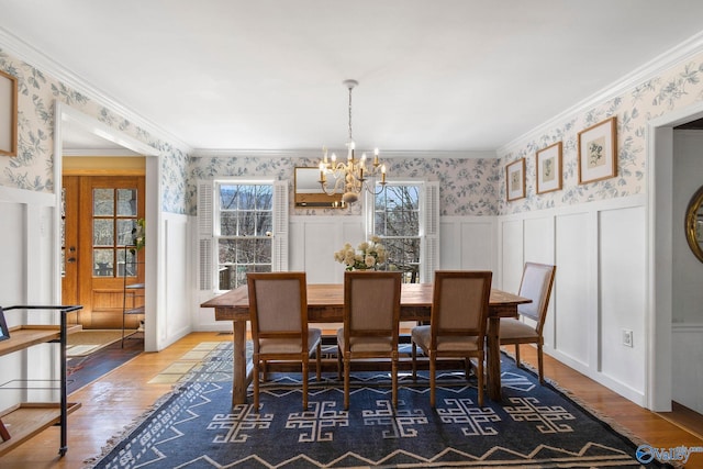 dining space featuring a notable chandelier, wood finished floors, wainscoting, wallpapered walls, and crown molding