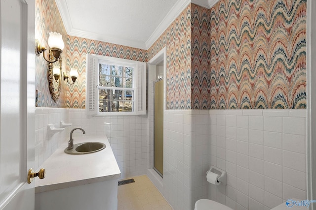 bathroom featuring wallpapered walls, ornamental molding, tile walls, and wainscoting