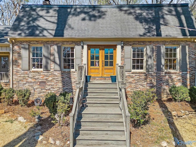 view of front facade with crawl space, roof with shingles, a chimney, and brick siding