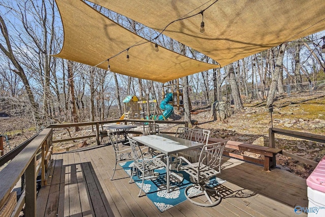 deck featuring outdoor dining area and a playground