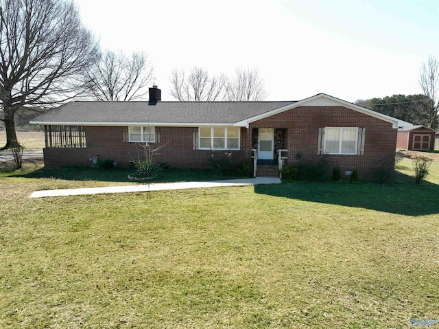 ranch-style home featuring brick siding, an outdoor structure, a storage unit, a front lawn, and a chimney