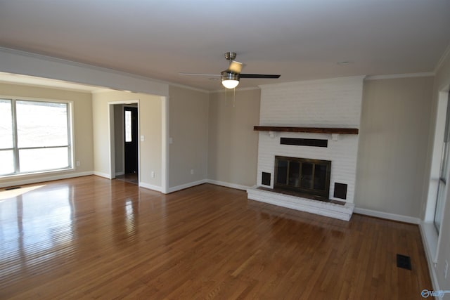 unfurnished living room featuring crown molding, dark wood-type flooring, ceiling fan, and a fireplace