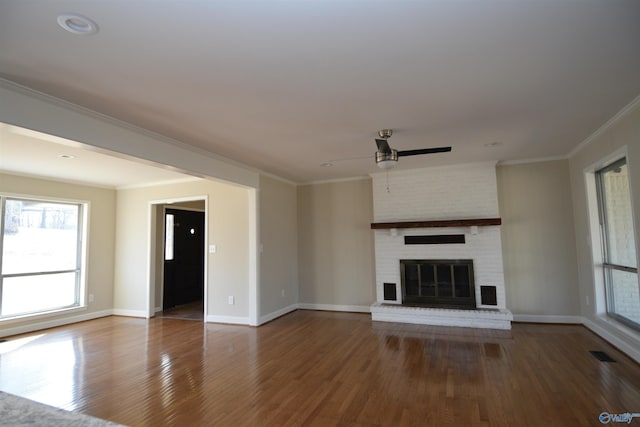 unfurnished living room with hardwood / wood-style flooring, ceiling fan, crown molding, and a brick fireplace