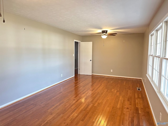 empty room with ceiling fan, hardwood / wood-style flooring, and a textured ceiling