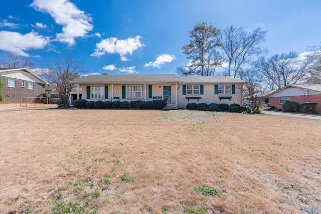 ranch-style house with brick siding, fence, and a front lawn