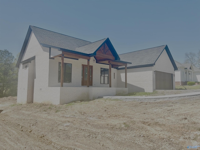 ranch-style home with brick siding, an attached garage, and a shingled roof