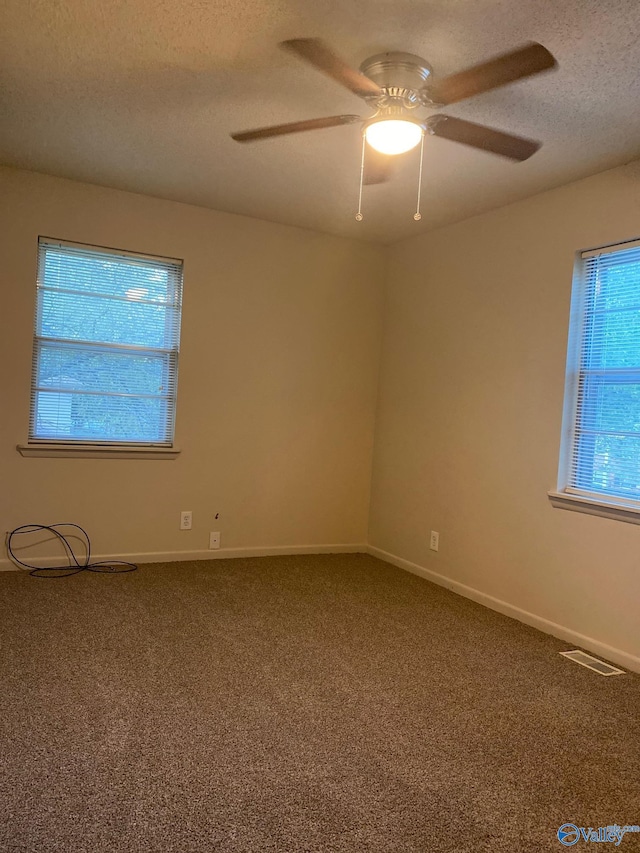 empty room featuring ceiling fan, a textured ceiling, and carpet flooring