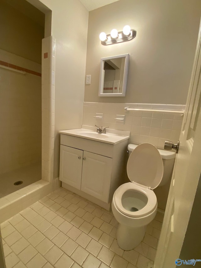 bathroom with tiled shower, vanity, toilet, and tile patterned floors