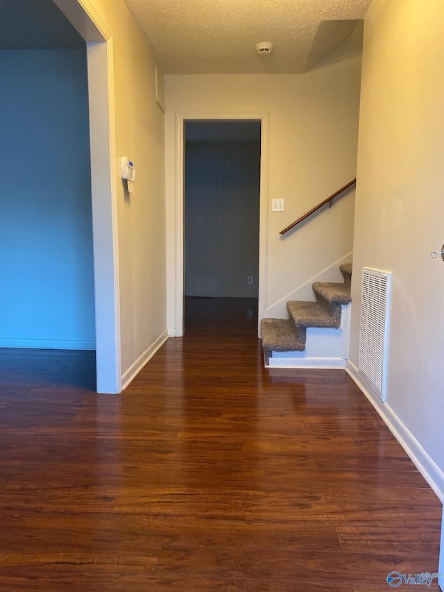 hall featuring a textured ceiling and dark hardwood / wood-style floors