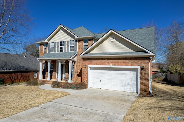 traditional-style home with fence, driveway, roof with shingles, a garage, and brick siding