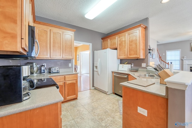 kitchen featuring a sink, a peninsula, light countertops, and stainless steel appliances