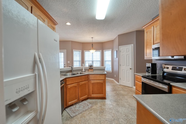 kitchen with decorative light fixtures, appliances with stainless steel finishes, a peninsula, a textured ceiling, and a sink