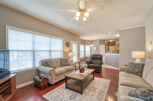 living room featuring plenty of natural light, dark wood-style floors, and visible vents