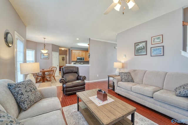 living area featuring baseboards, a ceiling fan, and light wood finished floors