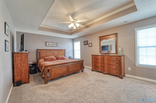 bedroom with visible vents, light colored carpet, a tray ceiling, and ornamental molding