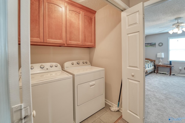 laundry area featuring ceiling fan, light carpet, washer and dryer, cabinet space, and a textured ceiling