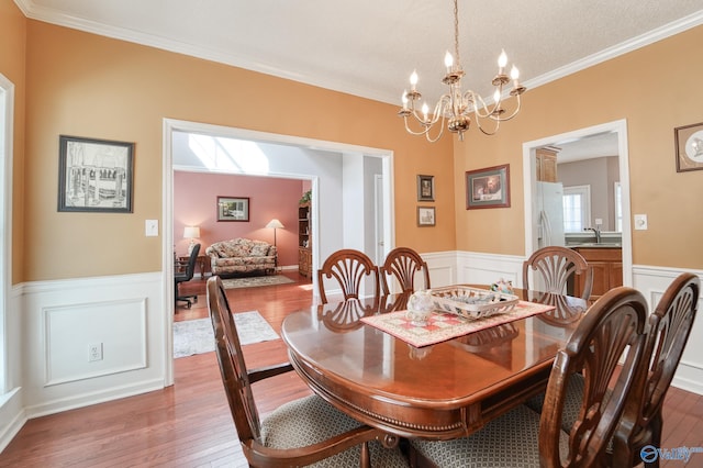 dining area featuring a wainscoted wall, crown molding, and hardwood / wood-style floors